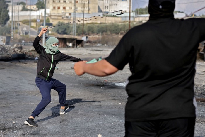 Palestinians using slingshots to throw stones towards Israeli soldiers during a protest in Ramallah, West Bank on October 18 2023