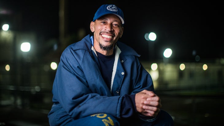 A man smiles with a navy blue hat and jacket