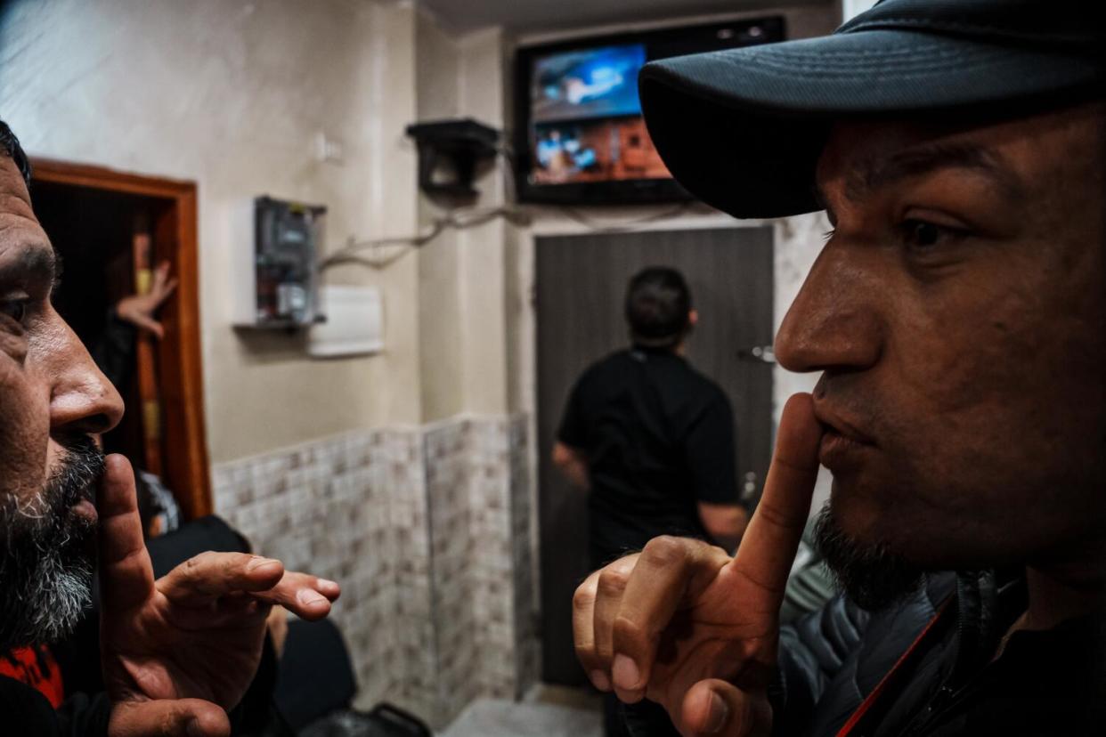 Family members of the Salaymah family signal each other to be quiet as Israeli security forces knock on their front door