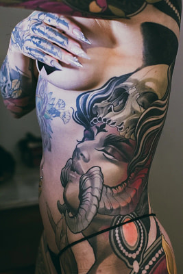 A realistic tattoo of a demon woman on the side of a woman's torso.