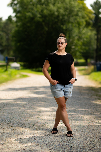 Tonia Miller stands on a gravel road with her legs crossed and hands in her pockets