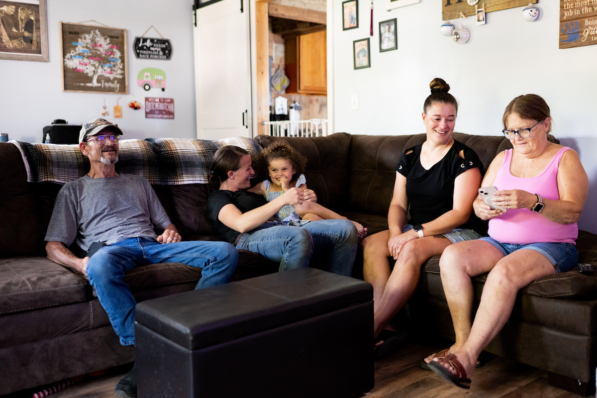 Tonia Miller sits on a sectional couch with her family