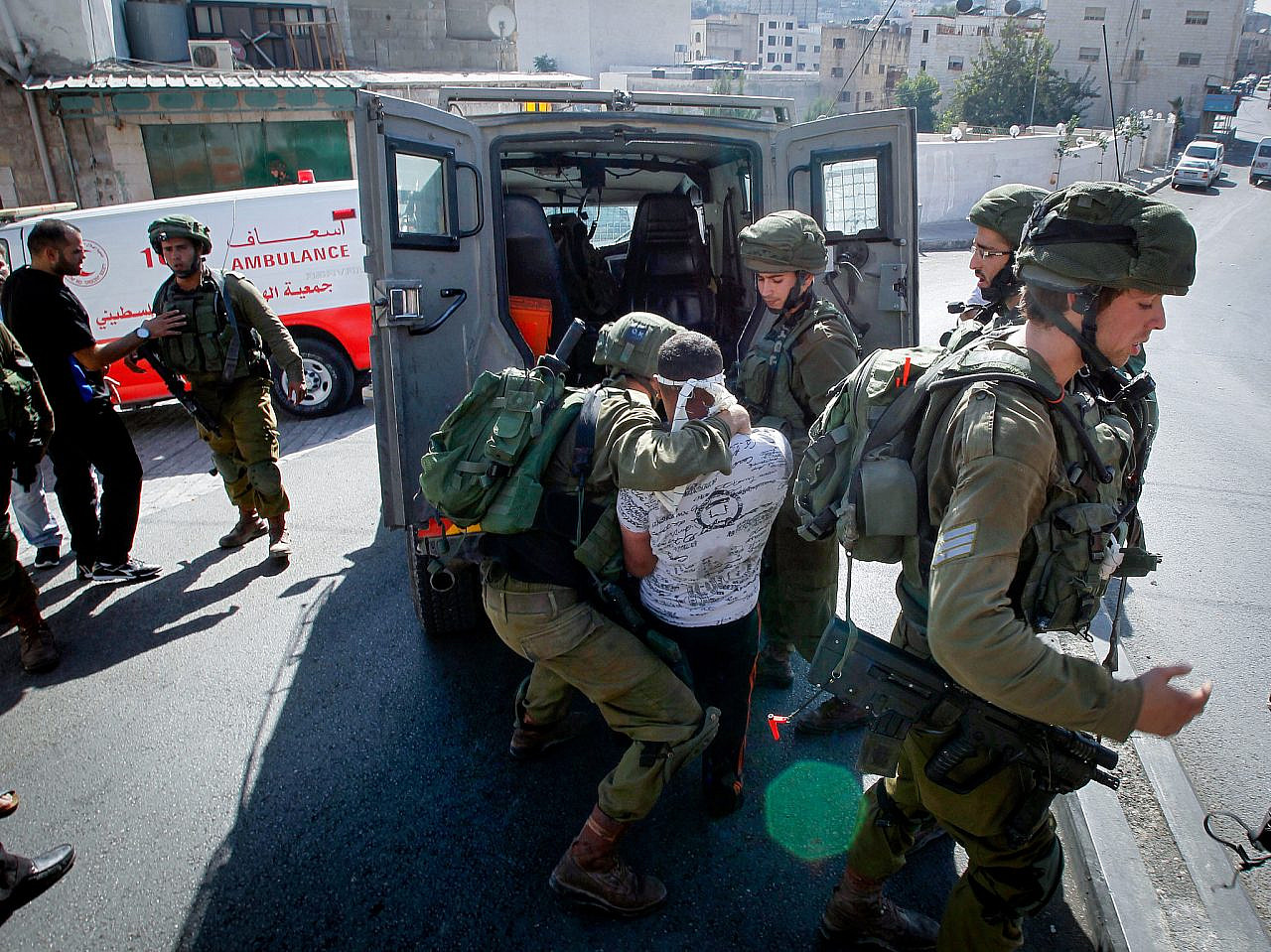 Israeli soldiers detain a Palestinian man following a house raid in the occupied West Bank city of Hebron, September 20, 2016. (Wisam Hashlamoun/Flash90)