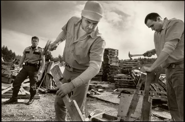 Two men recycle wooden pallets as part of the McNeil Island Prison's Work Ethic Program in 1995