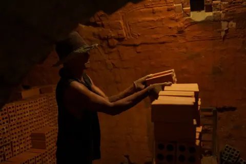 Thomas Cristofoletti/BBC A worker stacking bricks inside the kiln