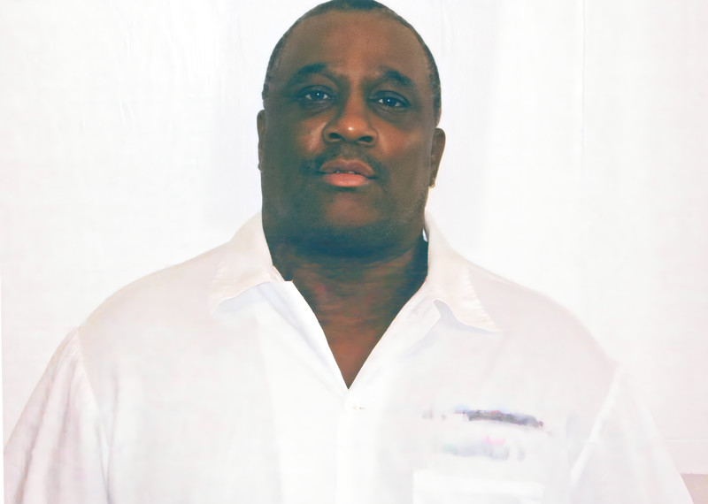 Rocky Myers wears a white shirt and stands against a white backdrop