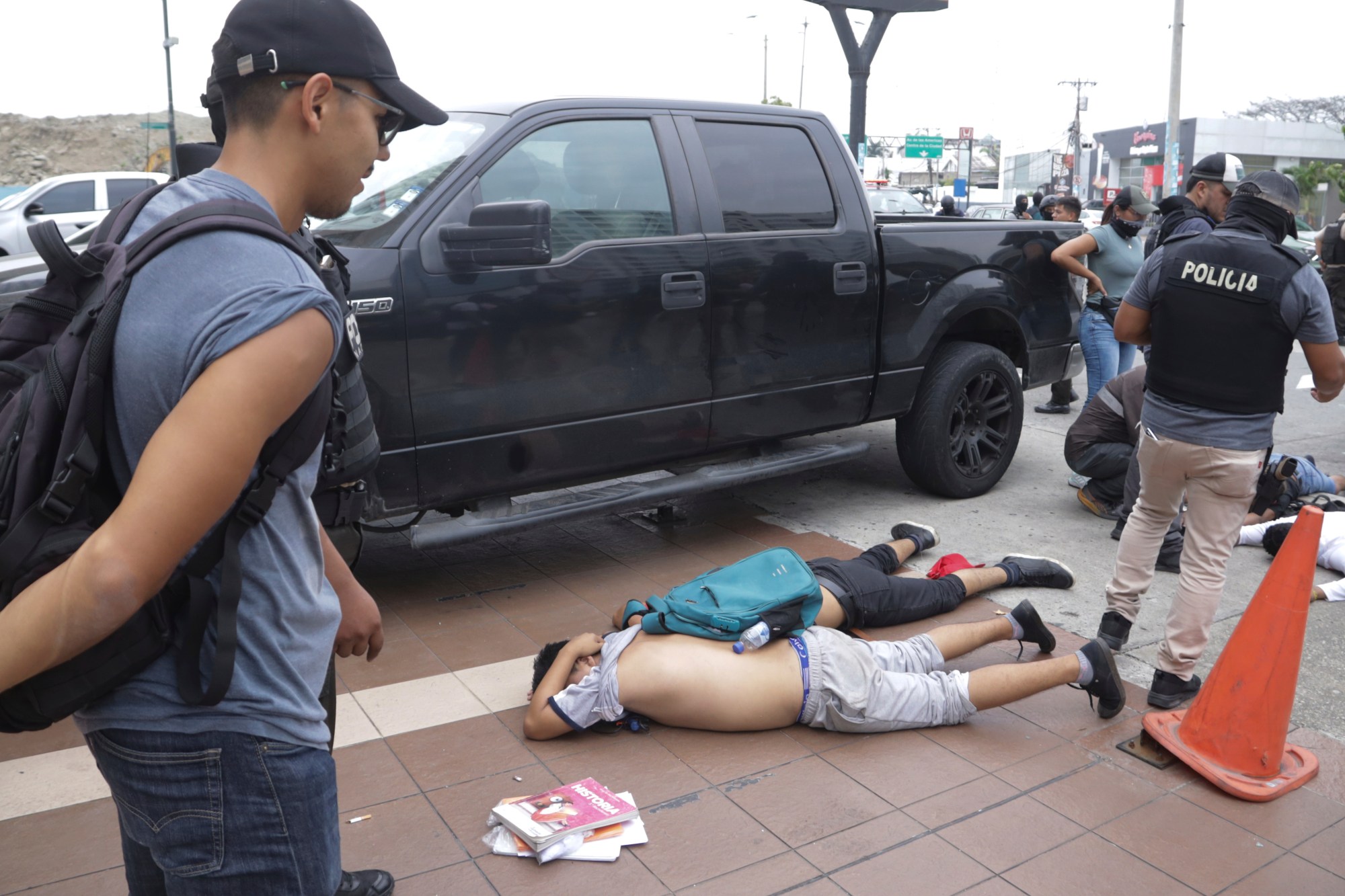 Men lie face down on the ground, detained by police outside TC Television, after a producer told police that they were part of a group who broke onto their set during a live broadcast, although they had not entered the station, in Guayaquil, Ecuador, Tuesday, Jan. 9, 2024. The country has seen a series of attacks after the government imposed a state of emergency in the wake of the apparent escape of a powerful gang leader from prison. (AP Photo/Cesar Munoz)