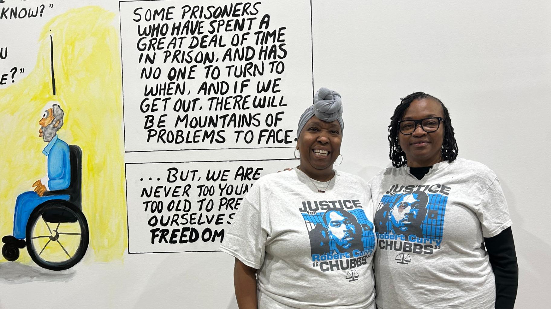 D’Andrea “Dee” Mosely (left) and Robin Adams (right), both aunts of artist Robert Curry, wear “Justice for Robert Curry” T-shirts at Walls Turned Sideways on Jan. 27, 2024. Family and loved ones say Curry has been incarcerated for nearly 20 years for a wrongful conviction. (Blair Paddock / WTTW News)