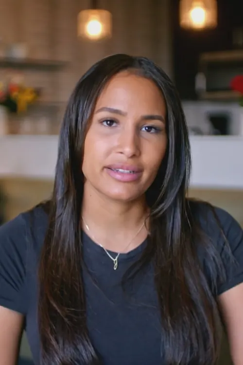 A person with long black hair looks at the camera