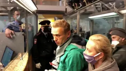 Reuters Law enforcement officers speaking with Russian opposition leader Alexei Navalny before leading him away at Sheremetyevo airport in Moscow, Russia January 17, 2021