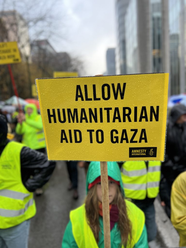 A demonstrator holds a yellow sign with the message 