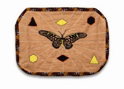 A quilt showing a butterfly at its center with radiating lines and shapes. 