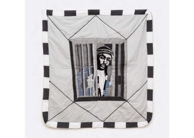 A quilt showing a man poking his out from a prison cell. 