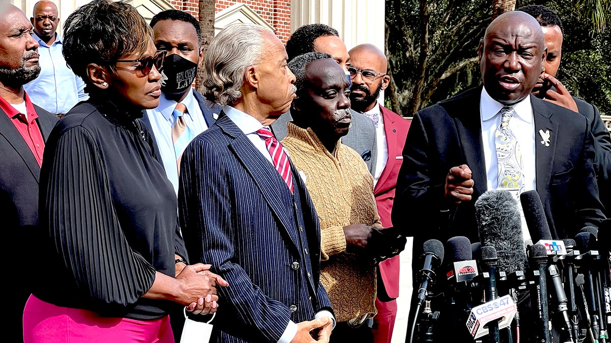 Family attorney Benjamin Crump, right, speaks as Marcus Arbery, second from right, his former wife Wanda Cooper, left, and the Rev. Al Sharpton listen outside the Glynn County courthouse,