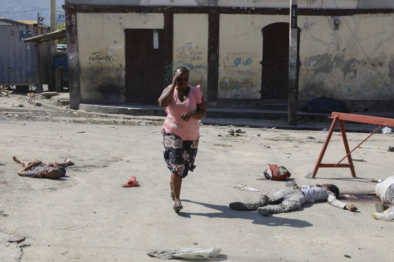 A woman walks past bodies of inmates outside the National Penitentiary in Port-au-Prince, Haiti, Sunday, March 3, 2024. Hundreds of inmates fled Haiti's main prison after armed gangs stormed the facility overnight. (AP Photo/Odelyn Joseph)