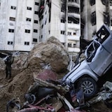 An Israeli soldier takes up a position next to a damaged car that is piled up with concrete as protection for Israeli soldiers next to UNRWA headquarters in Gaza on Feb. 8, 2024. 