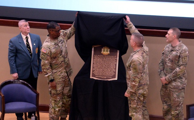 U.S. Disciplinary Barracks Historian Peter Grande, USDB Commandant Kevin Payne, Army Corrections Command Commanding General Maj. Gen. Duane R. Miller and ACC Command Sgt. Maj. Shawn Klosterman unveil the USDB sesquicentennial anniversary plaque during a ceremony May 21, 2024, at the Lewis and Clark Center at Fort Leavenworth, Kansas. The plaque will hang in the main entrance hall of the Old USDB. Photo by Prudence Siebert/Fort Leavenworth Lamp