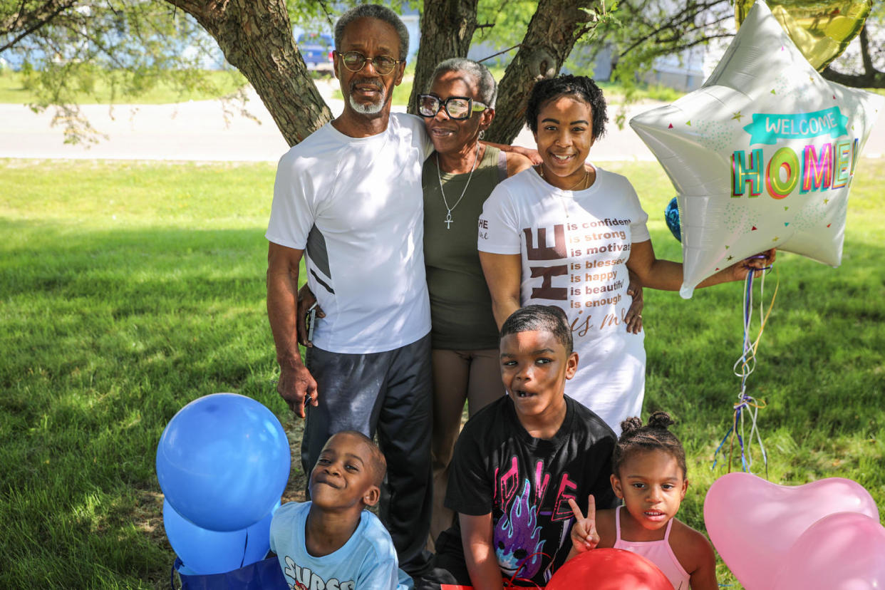 Reekila Harris-Dudley, right, stands for a portrait with her family outside, holding a balloon that says 