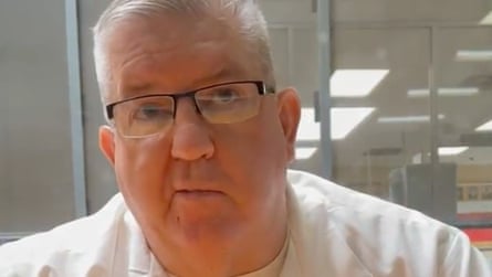 A man wearing glasses and a white shirt looks up