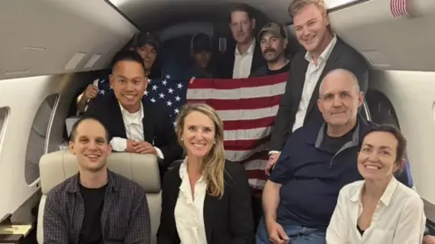 US government This image released by the White House shows Evan Gershkovich, left, Alsu Kurmasheva, right, and Paul Whelan, second from right, and others aboard a plane Thursday after their release from Russian captivity