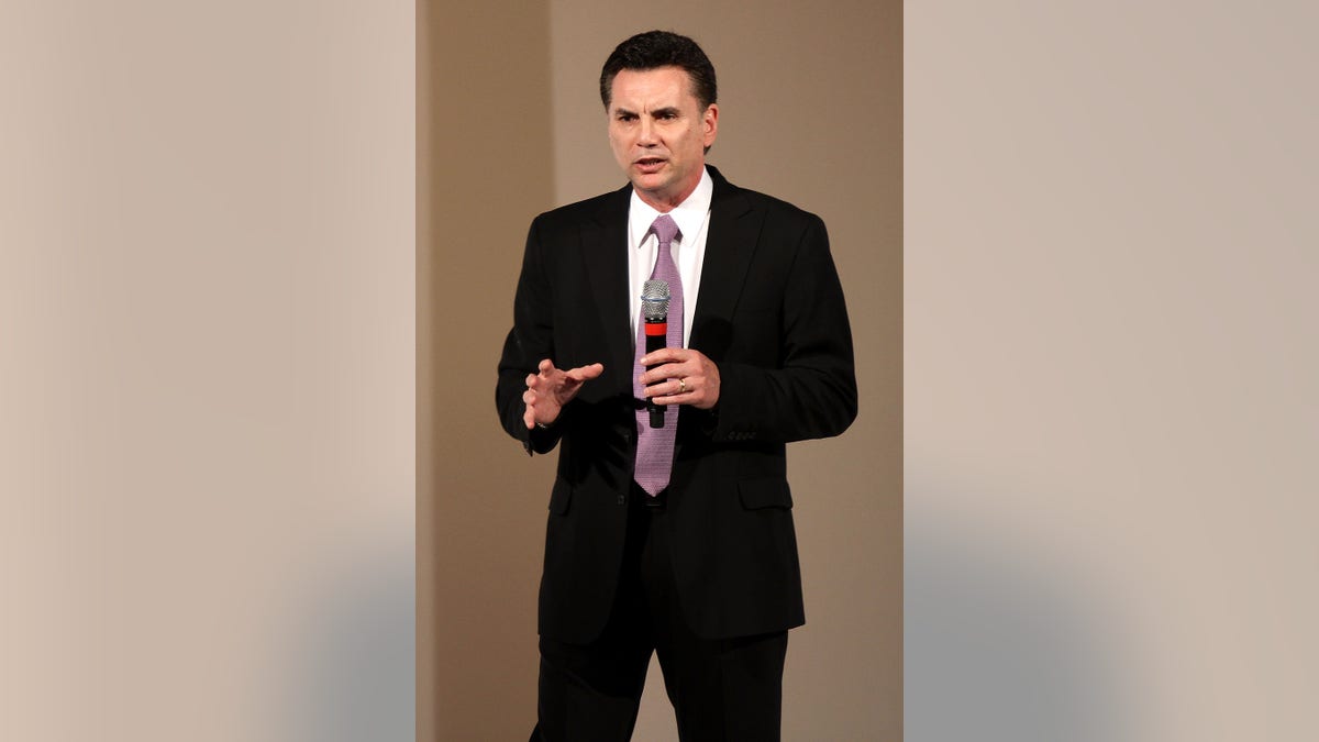 Michael Franzese wearing a suit and holding a mic.