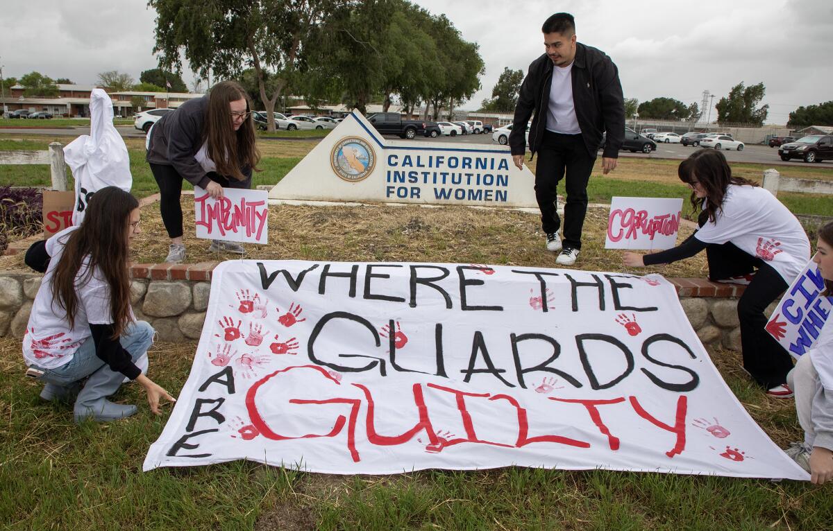 Protesters arrange a banner near a sign for the California Institution for Women.