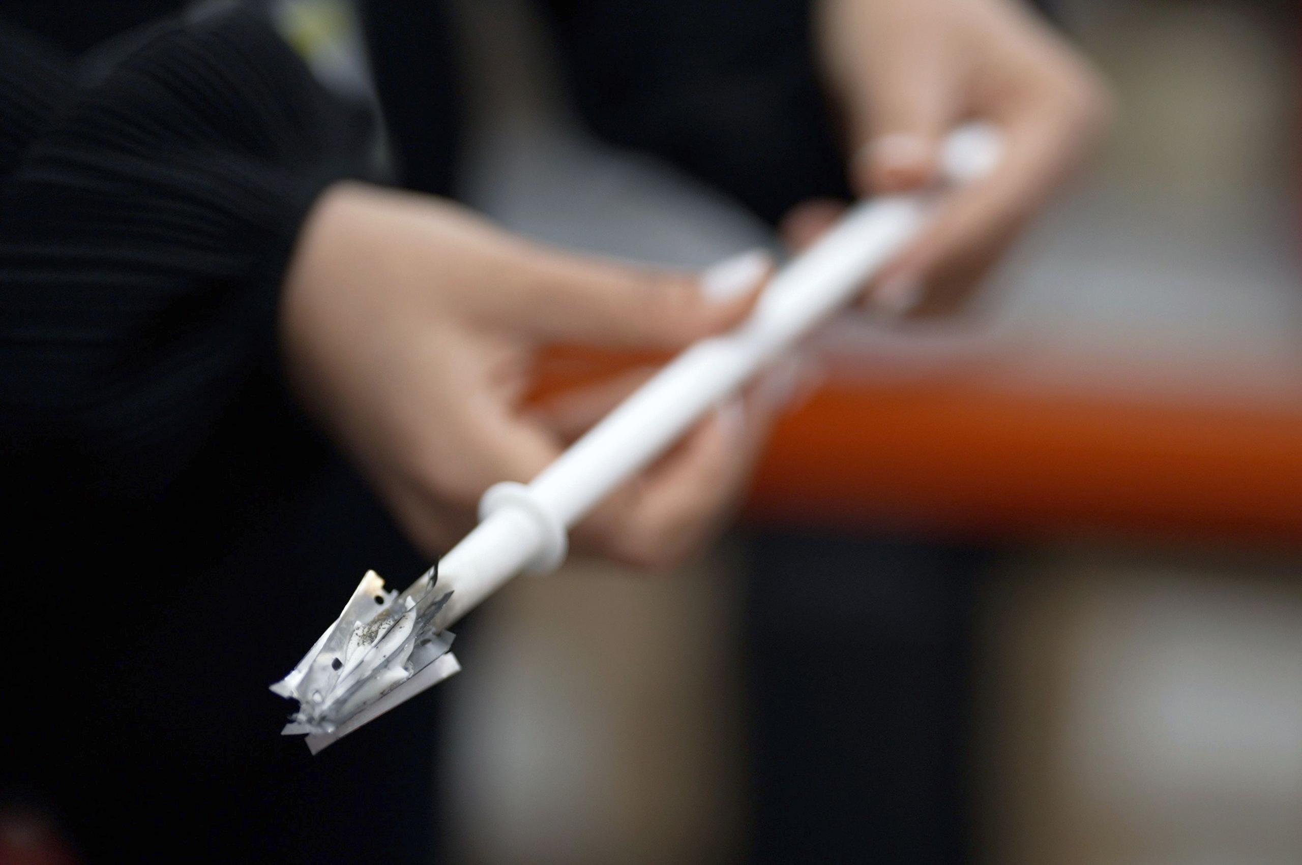 A prisoner officer's hands holding a weapon made from a toilet brush handle and razor blades