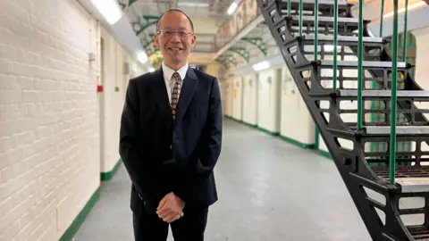 BBC Channing Bi stood in a suit in the hall of the jail