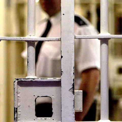 Getty Images A prison officer is seen behind a barred security door