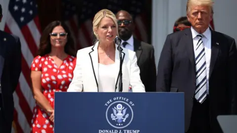 Getty Images Pam Bondi stands next to Donald Trump as she speaks during a press conference on 7 July, 2021