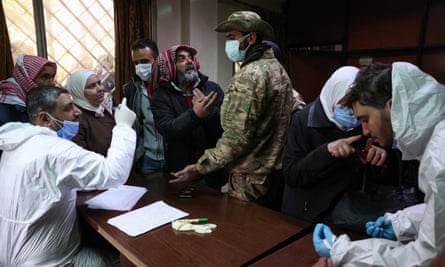 People looking for relatives talk to workers and an opposition fighter at the morgue of a hospital