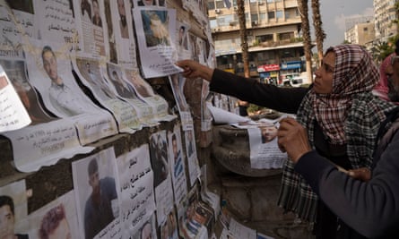 Hanaa places a photo of her brother, Hussam al-Khodr, among other pictures of missing people in Marjeh square