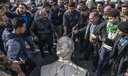 A group of Syrians looking at the toppled statue of Hafez al-Assad, the father of ousted president Bashar al-Assad