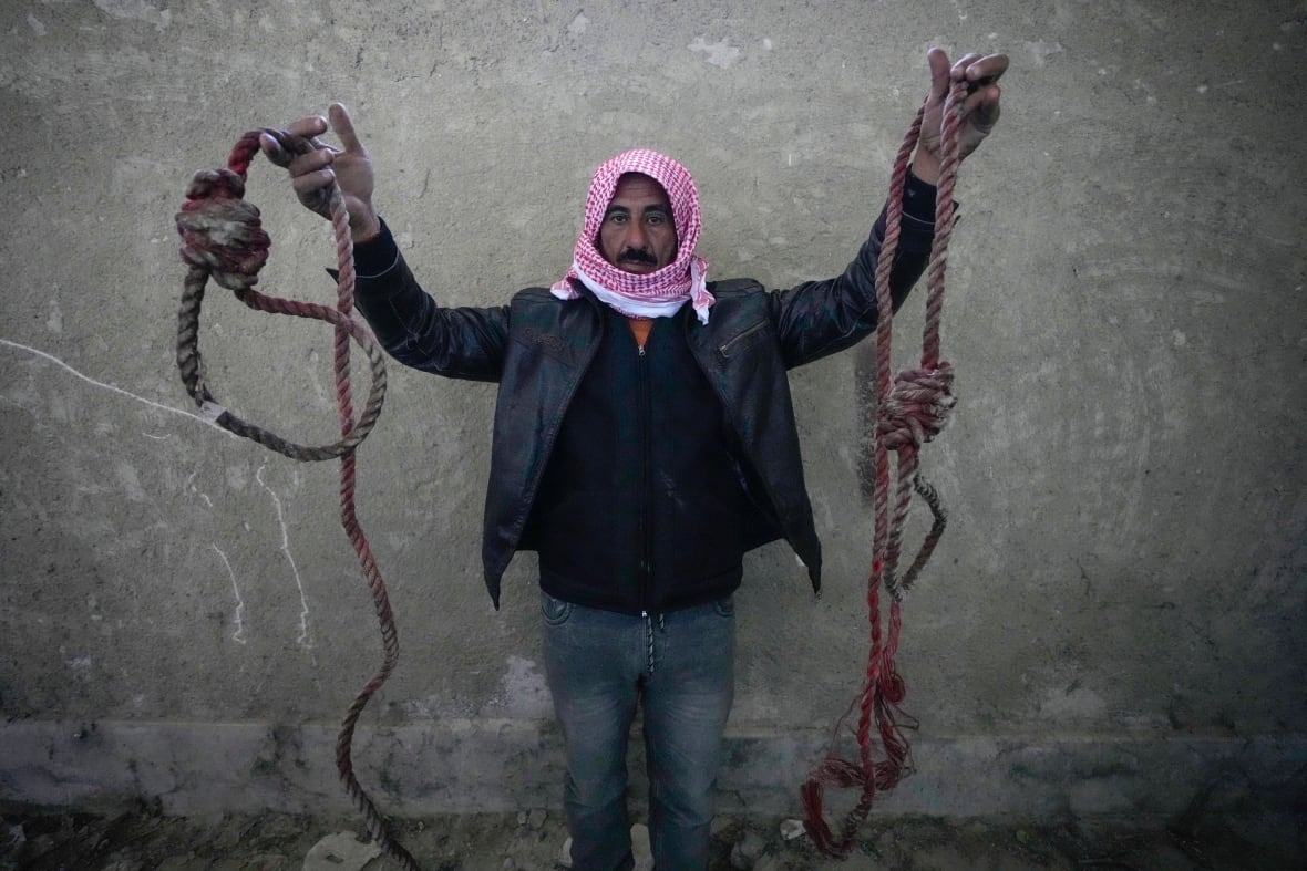 A Syrian relief worker holds up nooses found in the prison complex at Saydnaya, Syria, on Dec. 9, 2024.