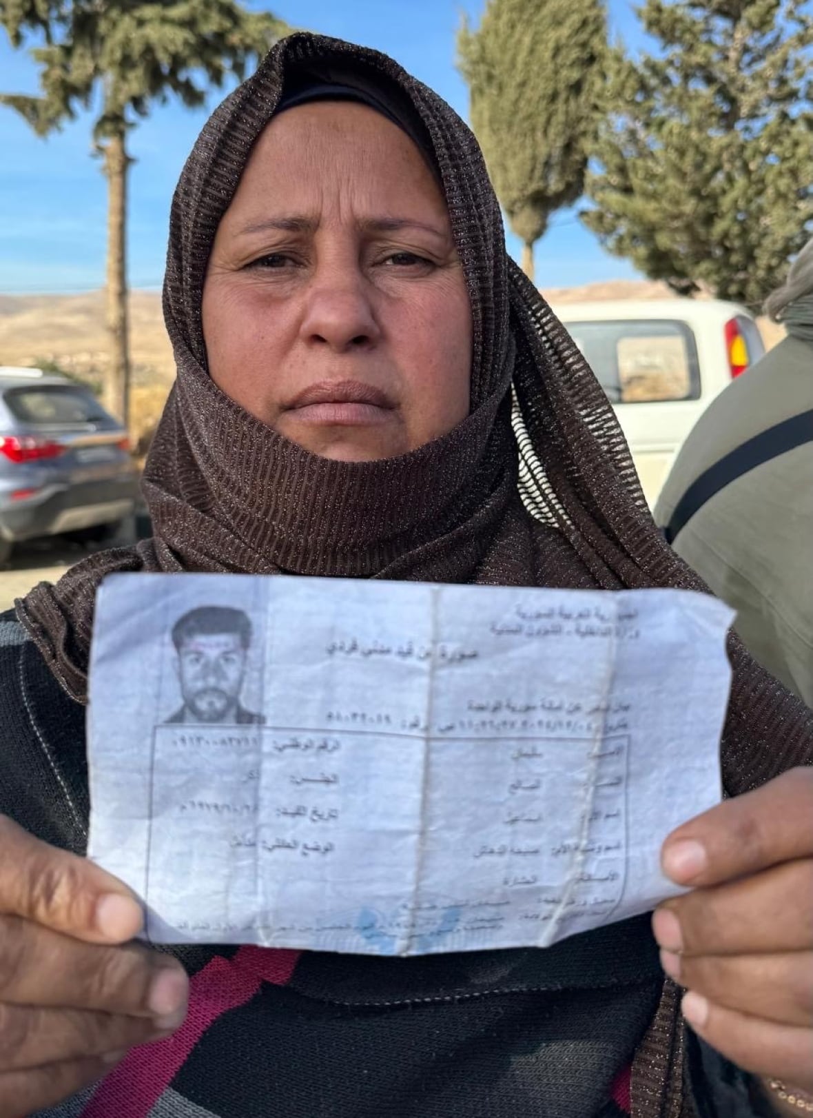 A woman holds a document bearing the face of a man