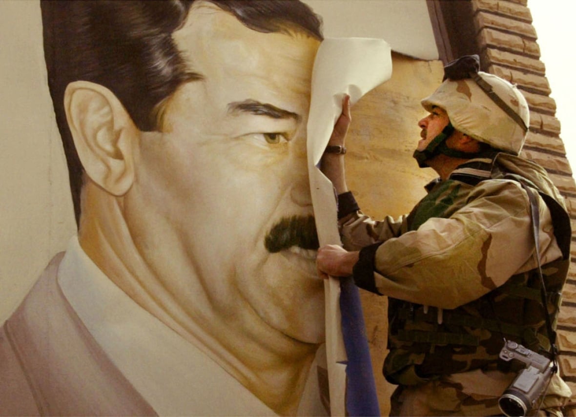 U.S. Marine Major Bull Gurfein pulls down a poster of Iraqi President Saddam Hussein March 21, 2003 in Safwan, Iraq. 