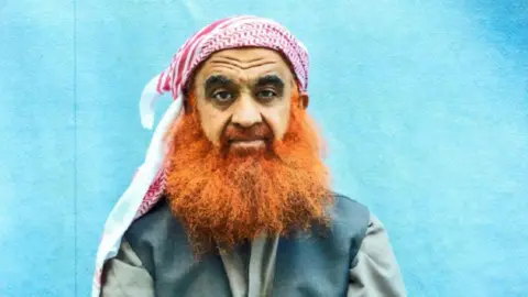 Photo courtesy of Khalid Sheikh Mohammed’s legal team Khalid Sheikh Mohammed has a bushy orange beard and wears a red and white headscarf 