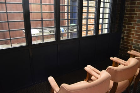 Two chairs facing toward a room with metal bars across windows and a strectcher