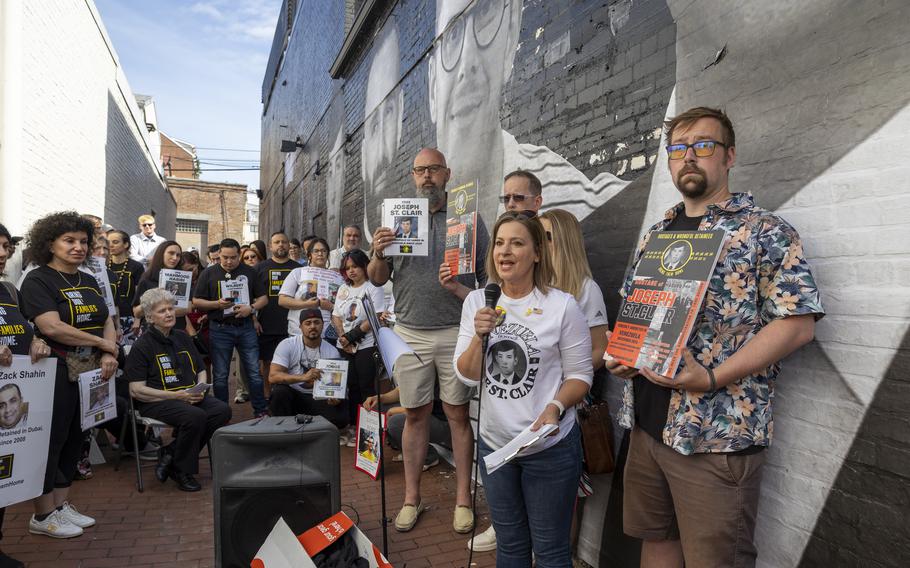 A woman speaks to a group of people standing in an alley and participating in a rally.