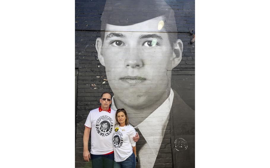 Two people standing in front of a mural on the side of a building.