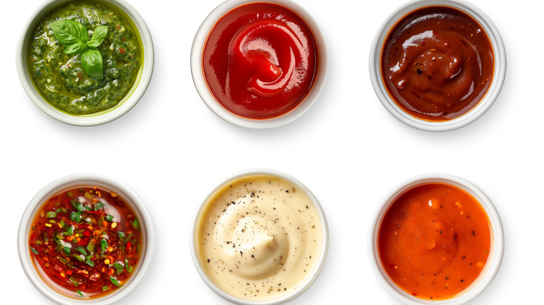 Cups of dipping sauces and condiments like salsa verde, mayo, and hot sauce